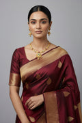 traditional gold-toned jewelry set featuring a necklace with square stations set with ruby-red and clear stones, leading to a large, intricate gold pendant. The set includes matching Jhumka earrings with red stone accents.