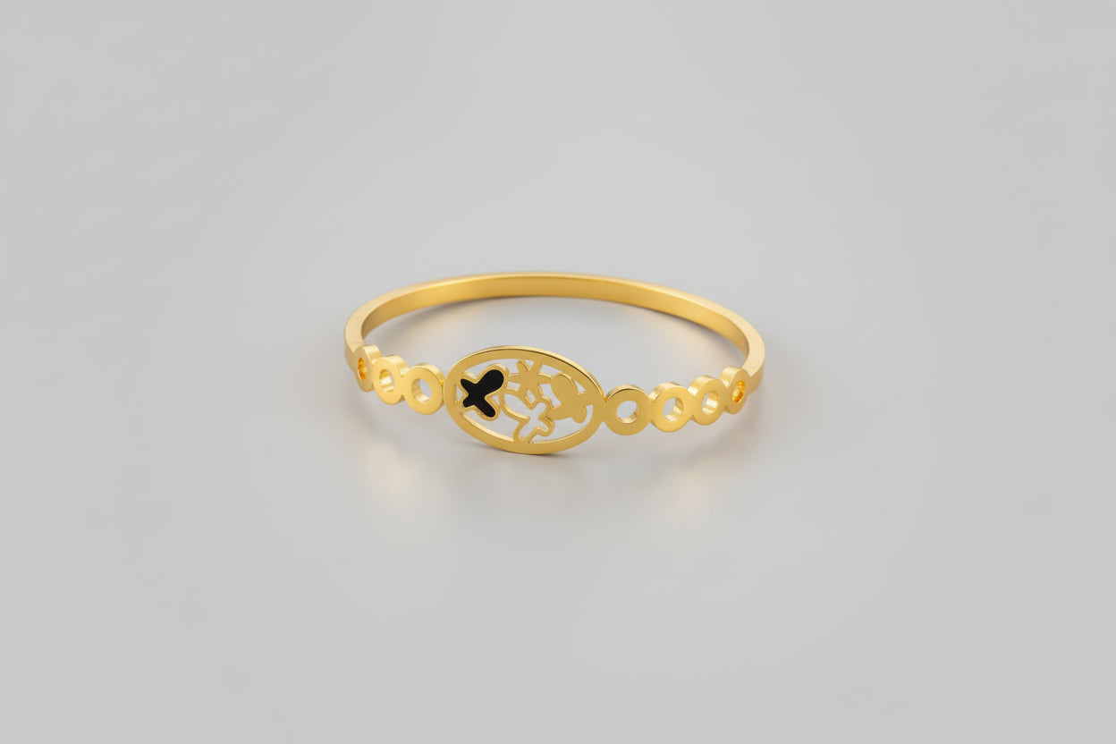 A dainty gold-toned open-cuff bangle featuring a central multi-petaled floral motif and two smaller four-leaf clover charms on either side, displayed on a vibrant pink background.