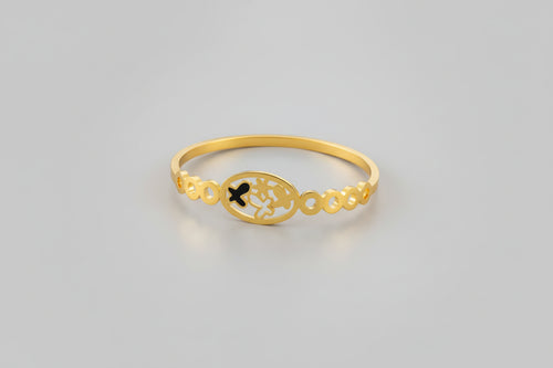 A dainty gold-toned open-cuff bangle featuring a central multi-petaled floral motif and two smaller four-leaf clover charms on either side, displayed on a vibrant pink background.