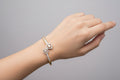 Gold bracelet with heart-shaped gemstones on a green fabric background