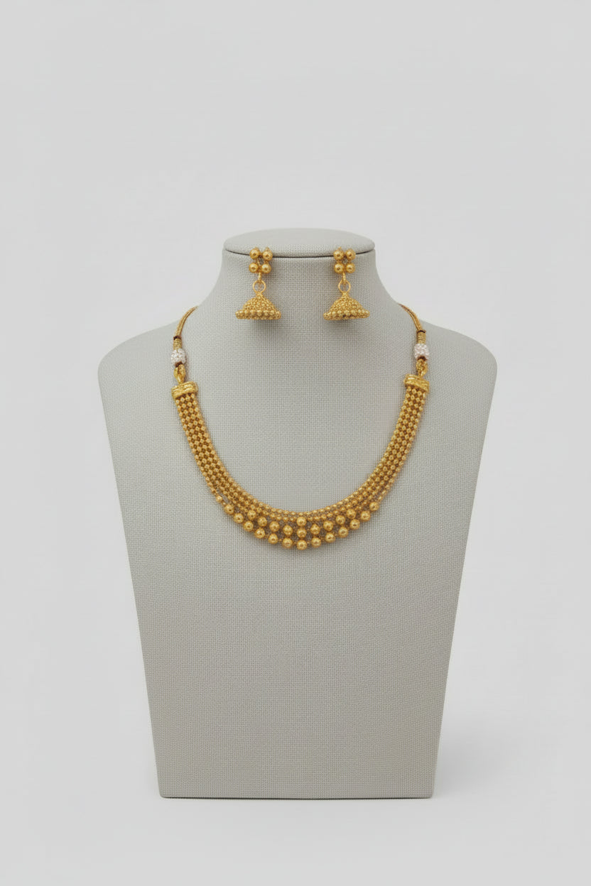A modern gold-toned choker necklace featuring four layered strands of polished round beads that graduate in size toward the center, shown worn on a neck against an orange and white background.