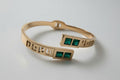 Rose gold bracelet with green stones on a textured white surface