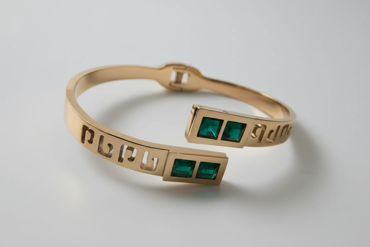 Rose gold bracelet with green stones on a textured white surface