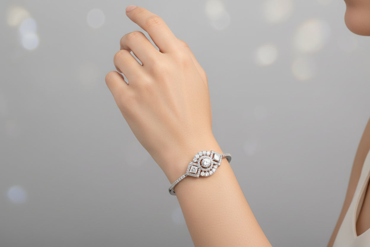 A silver-toned statement bangle with a large central circular cluster of clear crystals flanked by two diamond-shaped stones, featuring a fully encrusted band on a dark textured surface
