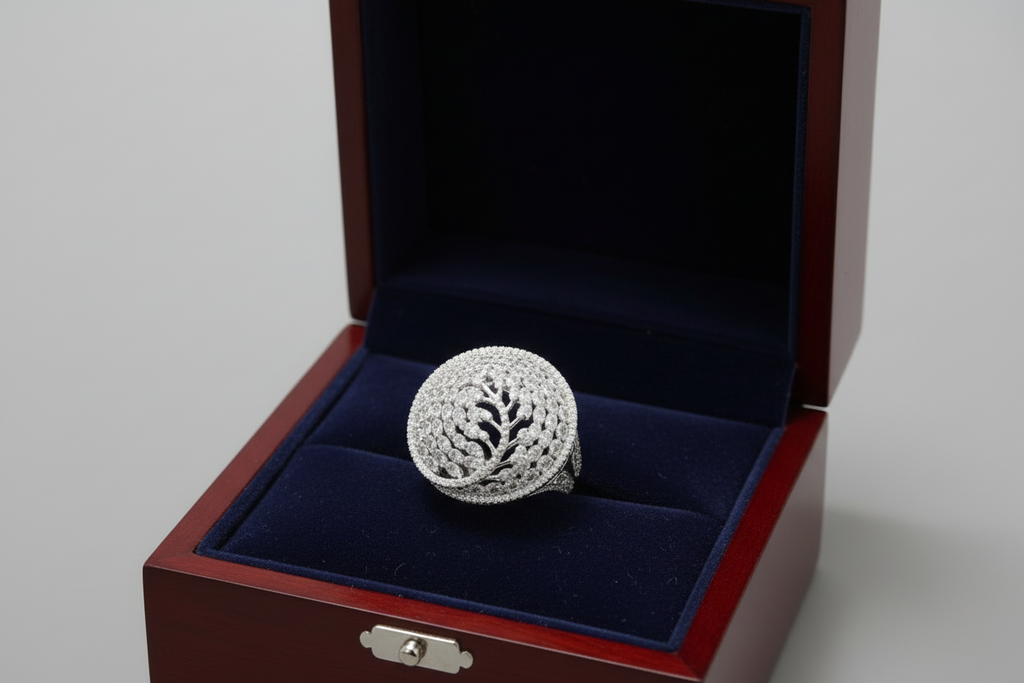 Hand wearing a large, ornate silver ring with intricate design on a dark background