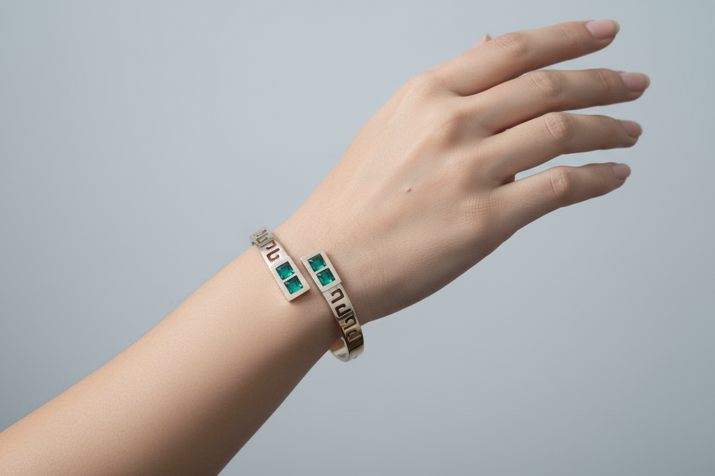 Bracelet with green gemstones on a wrist against a purple fabric background