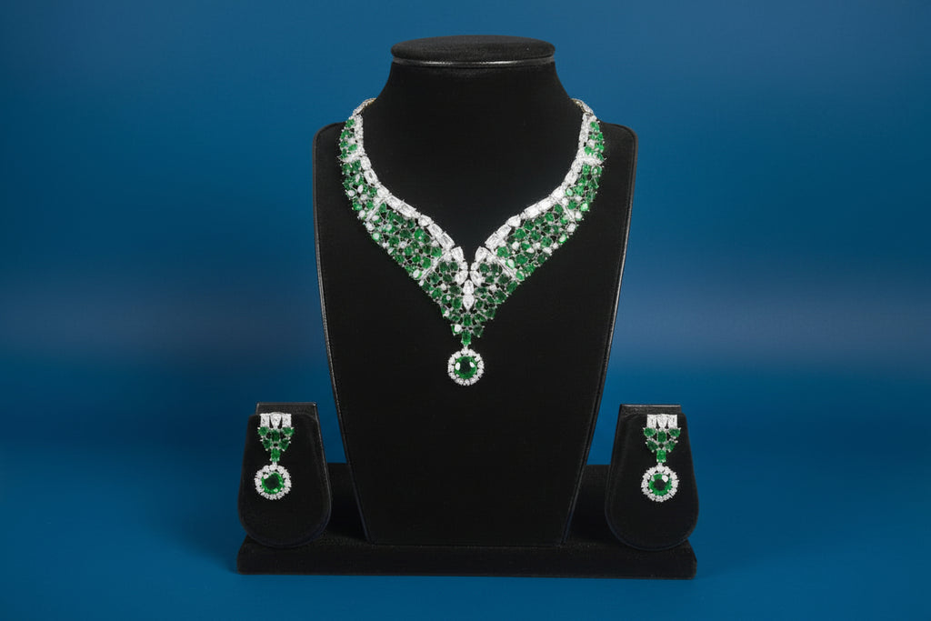 Green and silver necklace and earrings on a black stand against a blue background