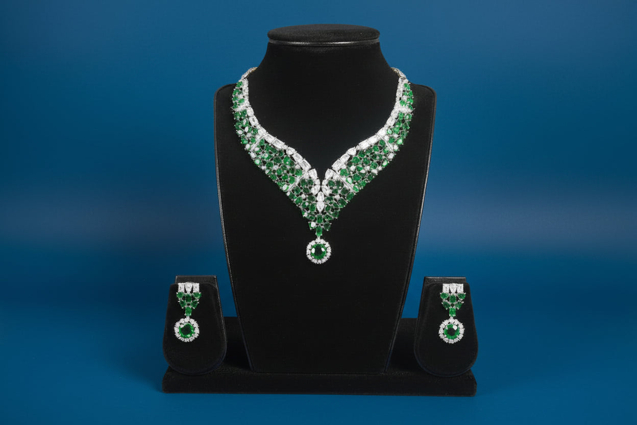 Green and silver necklace and earrings on a black stand against a blue background