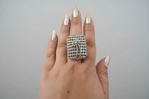 Hand wearing a large diamond ring on a green background