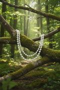 Pearl necklace and earrings on a blue mannequin with a blurred indoor background